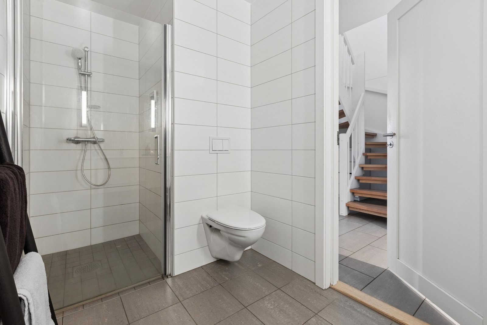 Badet er fra byggeår, med flislagt gulv med gulvvarme. Dusjnisje med glassdør, vegghengt dusjarmatur og vegghengt toalett Galleribilde