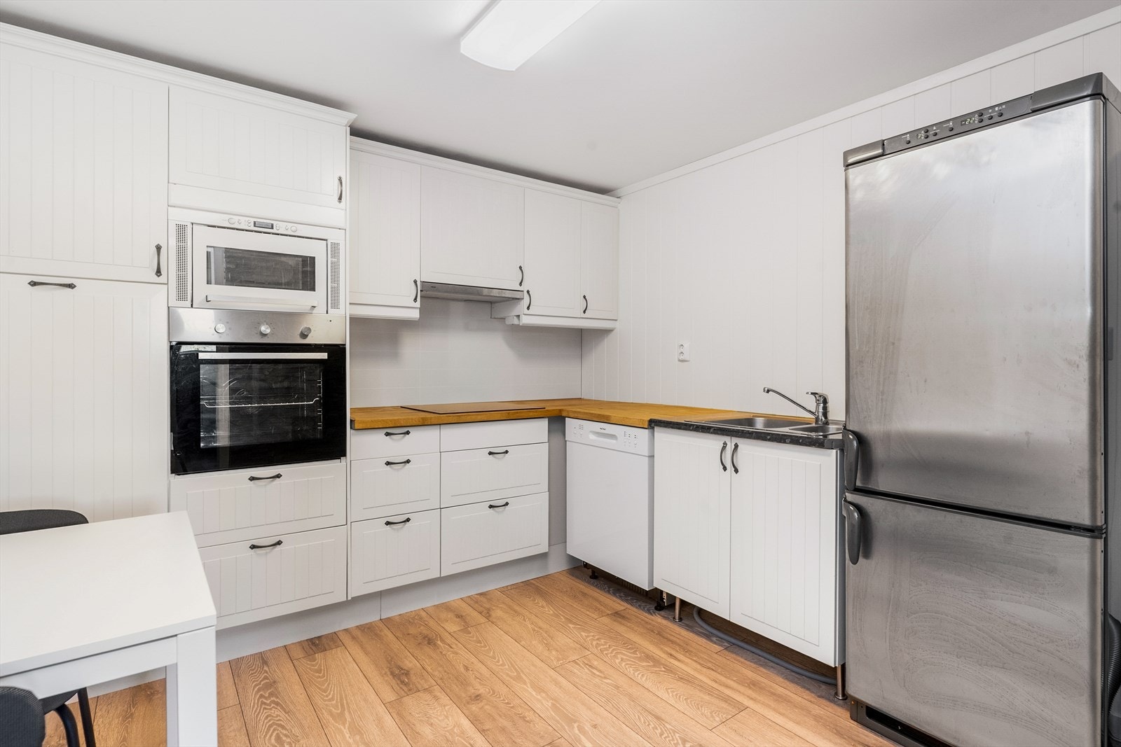 Kjøkkenet i leiligheten har innredning med profilerte fronter, benkeplate i heltre og laminat, og opplegg for oppvaskmaskin. Galleribilde