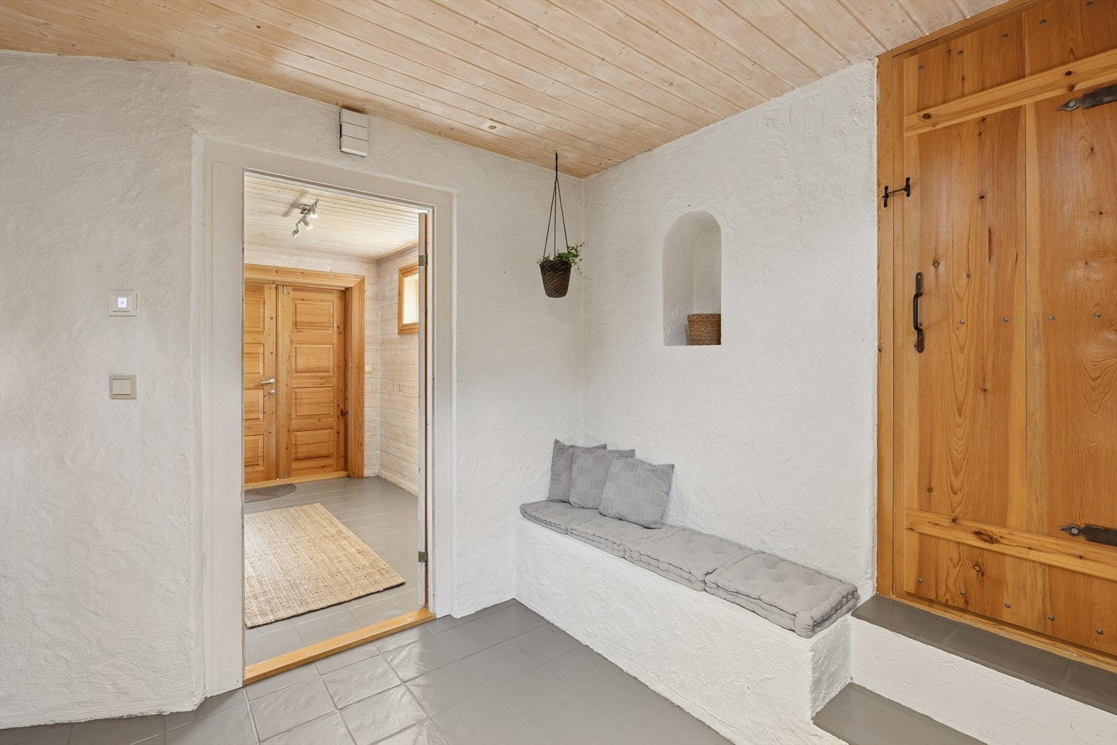 Innenfor møter du en romslig entré med flislagt gulv, hvitpussede vegger og panel i himlingen. Galleribilde