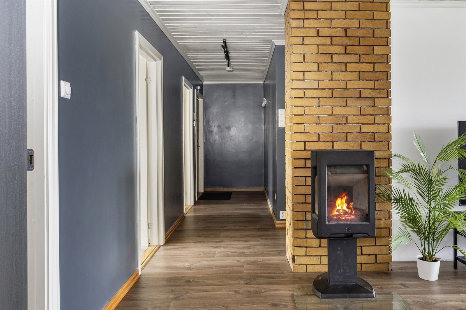 Fra gangen åpner det seg opp mot stuen, hvor peisovnen blir et naturlig midtpunkt. Galleribilde