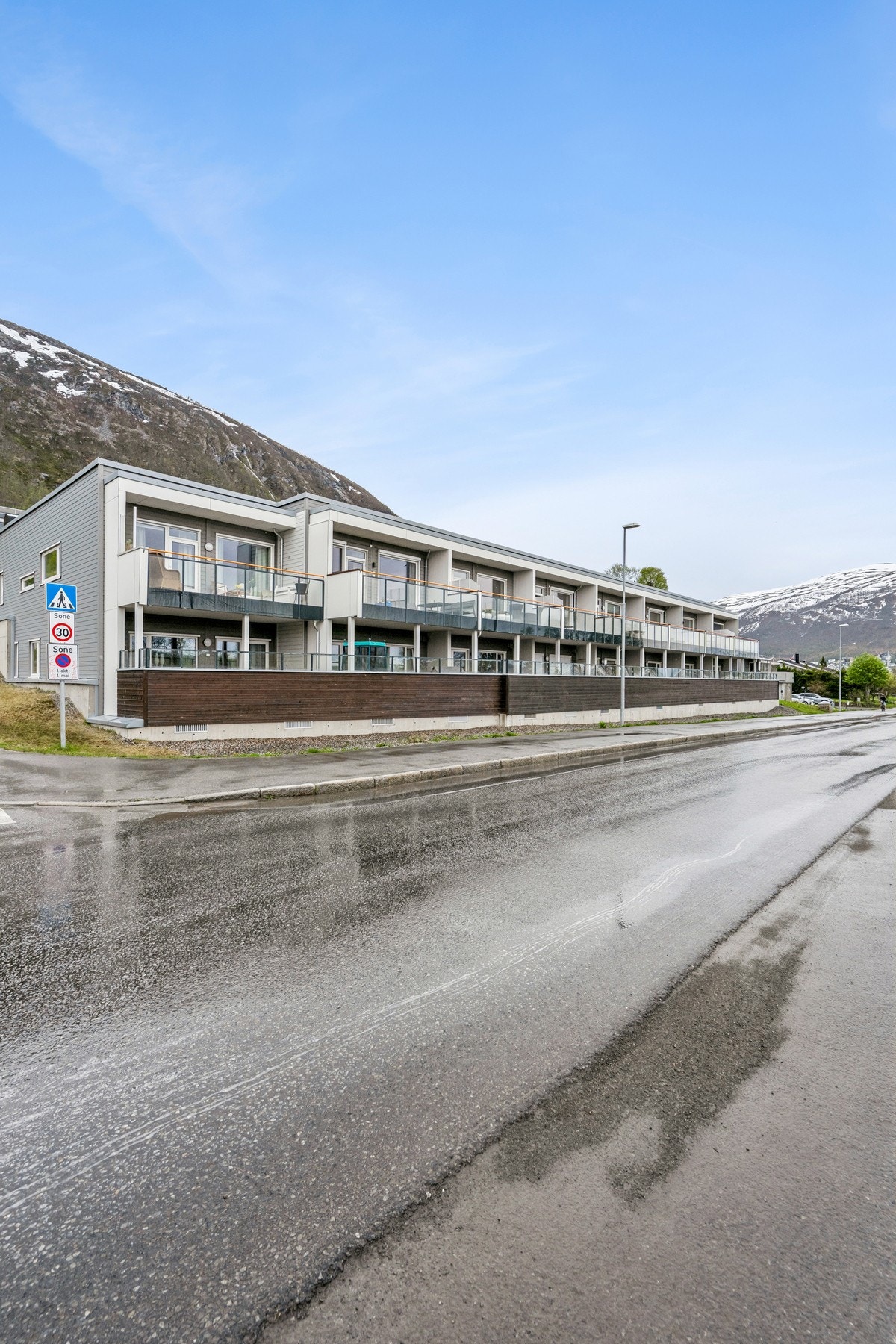 Rekkehuset ligger i et skrånende terreng med asfaltert adkomst. Galleribilde