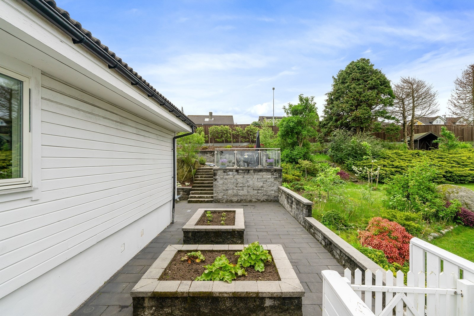 Fra stuen er det utgang til hagen og en steinbelagt uteplass med plantekasser. Galleribilde