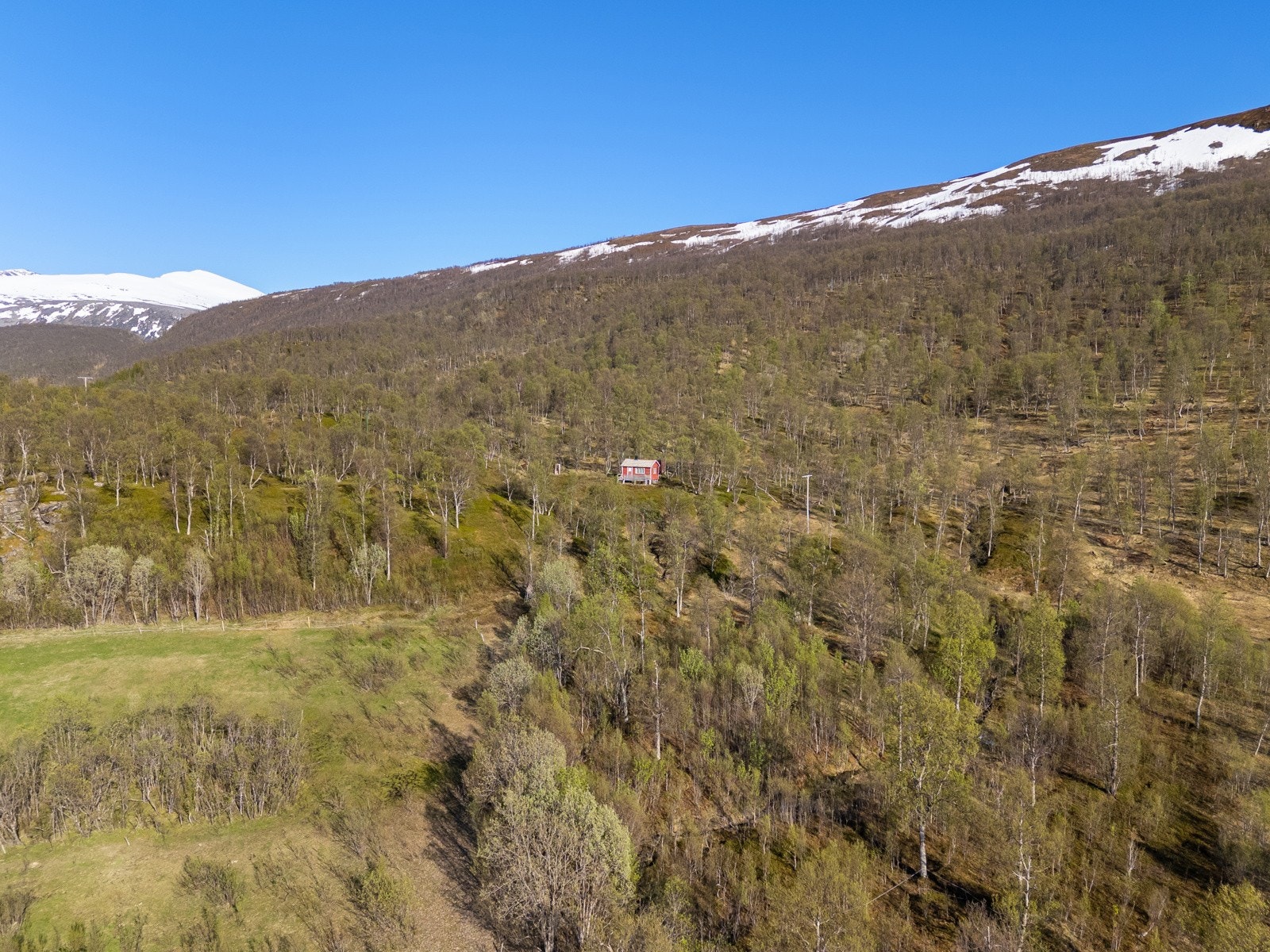 Lett kupert og delvis skrånende terreng omgitt av skog og naturlig vegetasjon. Opparbeidet med enkel hyttebebyggelse og uthus. Galleribilde