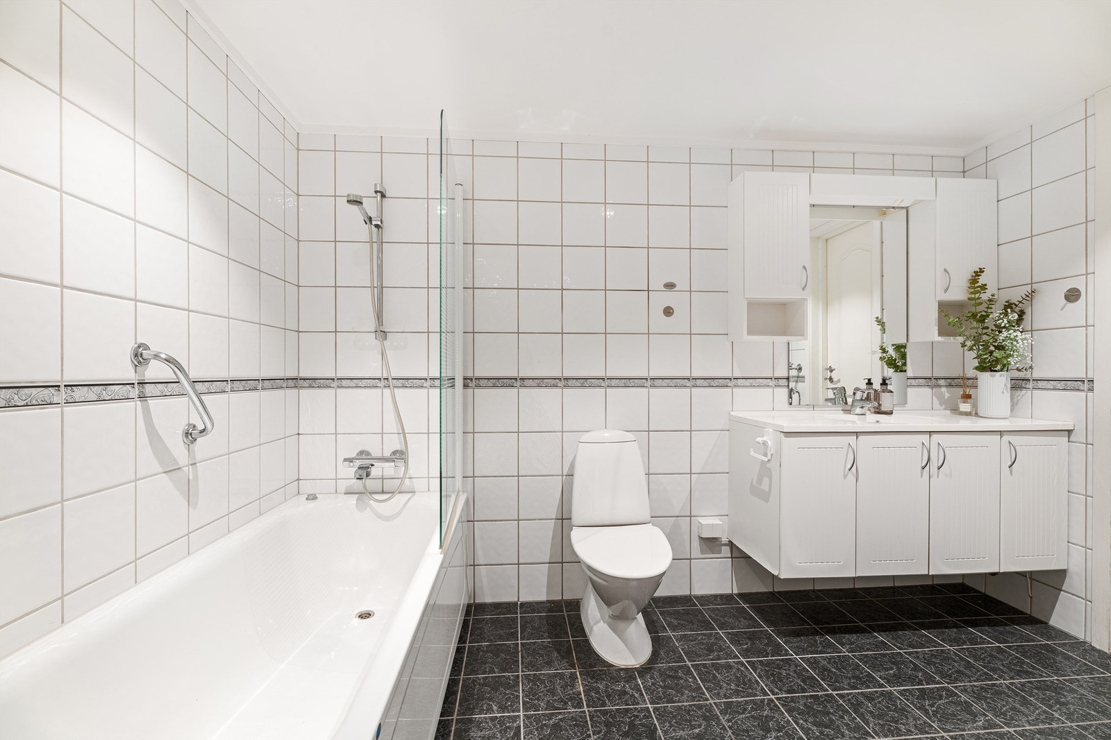 Videre er det stående toalett samt badekar med dusjvegg. Galleribilde
