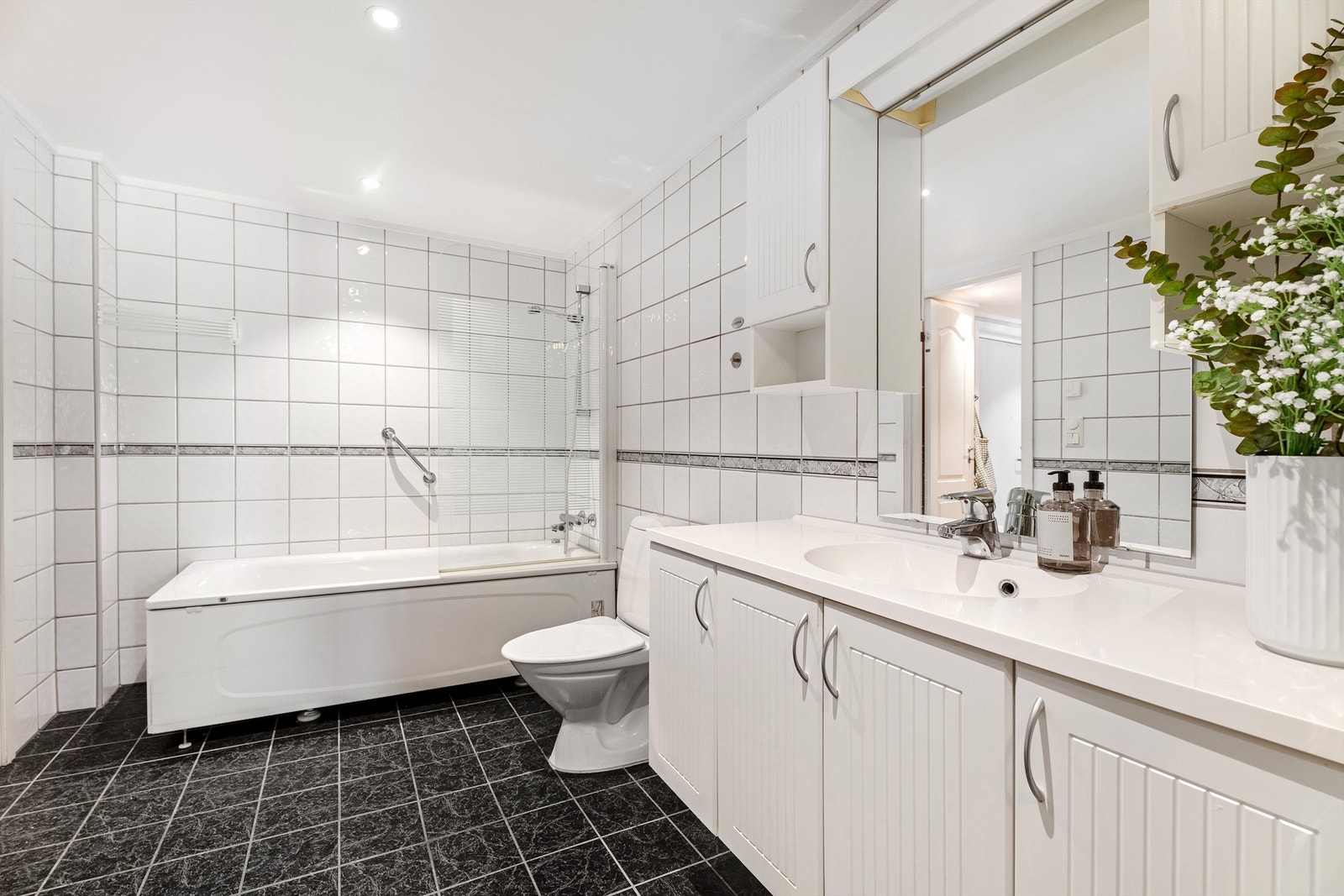 Badet er flislagt og har en større servant med oppbevaring samt tilhørende overskap. Galleribilde