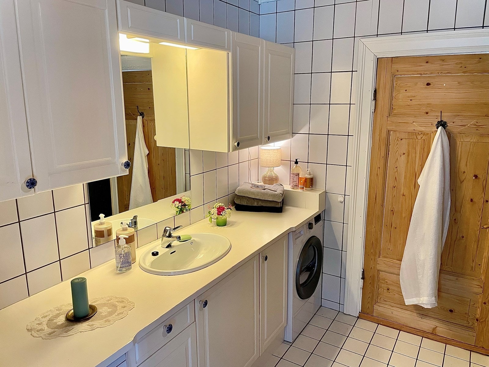 Lyst, helfliset baderom med varmekabler i gulv. Badet er utstyrt med servant over innredning, speil med overliggende belysning, vegghengt skap, toalett og dusjkabinett. Det er opplegg til vaskemaskin og tørketrommel under benkeplaten Galleribilde