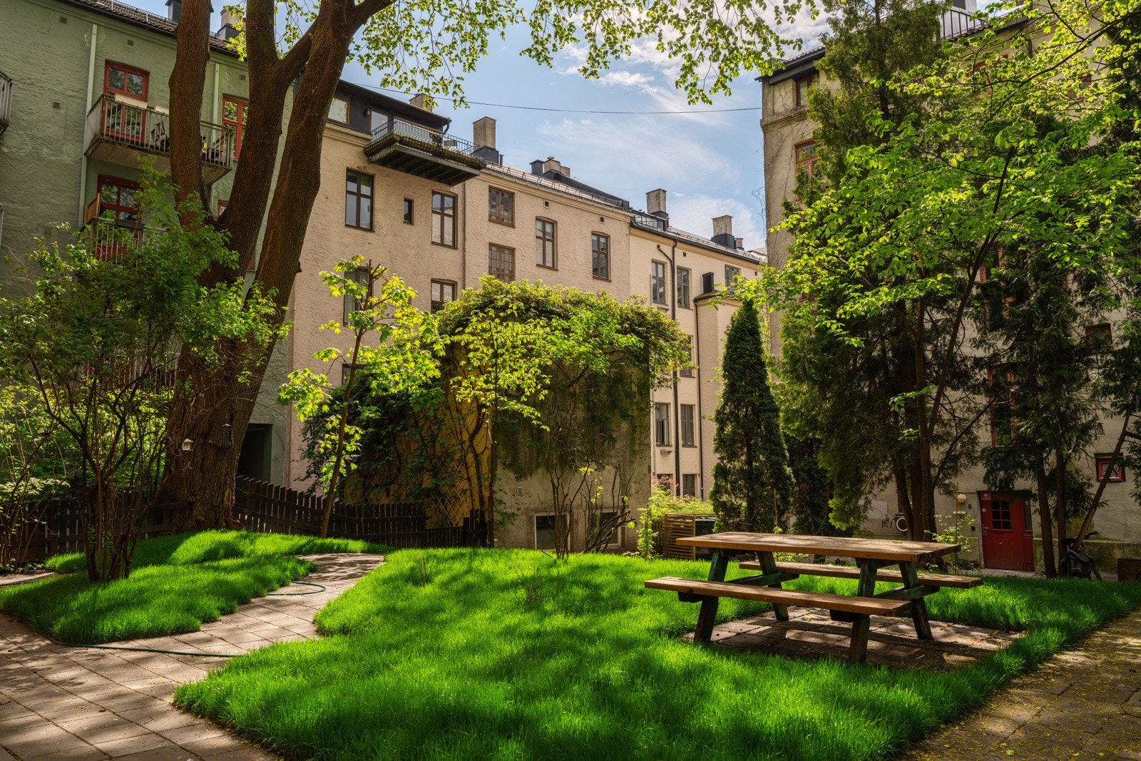 Hyggelig bakgård opparbeidet med gressplen, beplantning og sittegruppe. Galleribilde