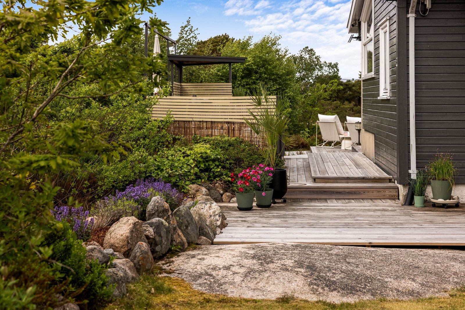 Det er pent opparbeidet naturtomt med busker, bedd og blomster Galleribilde