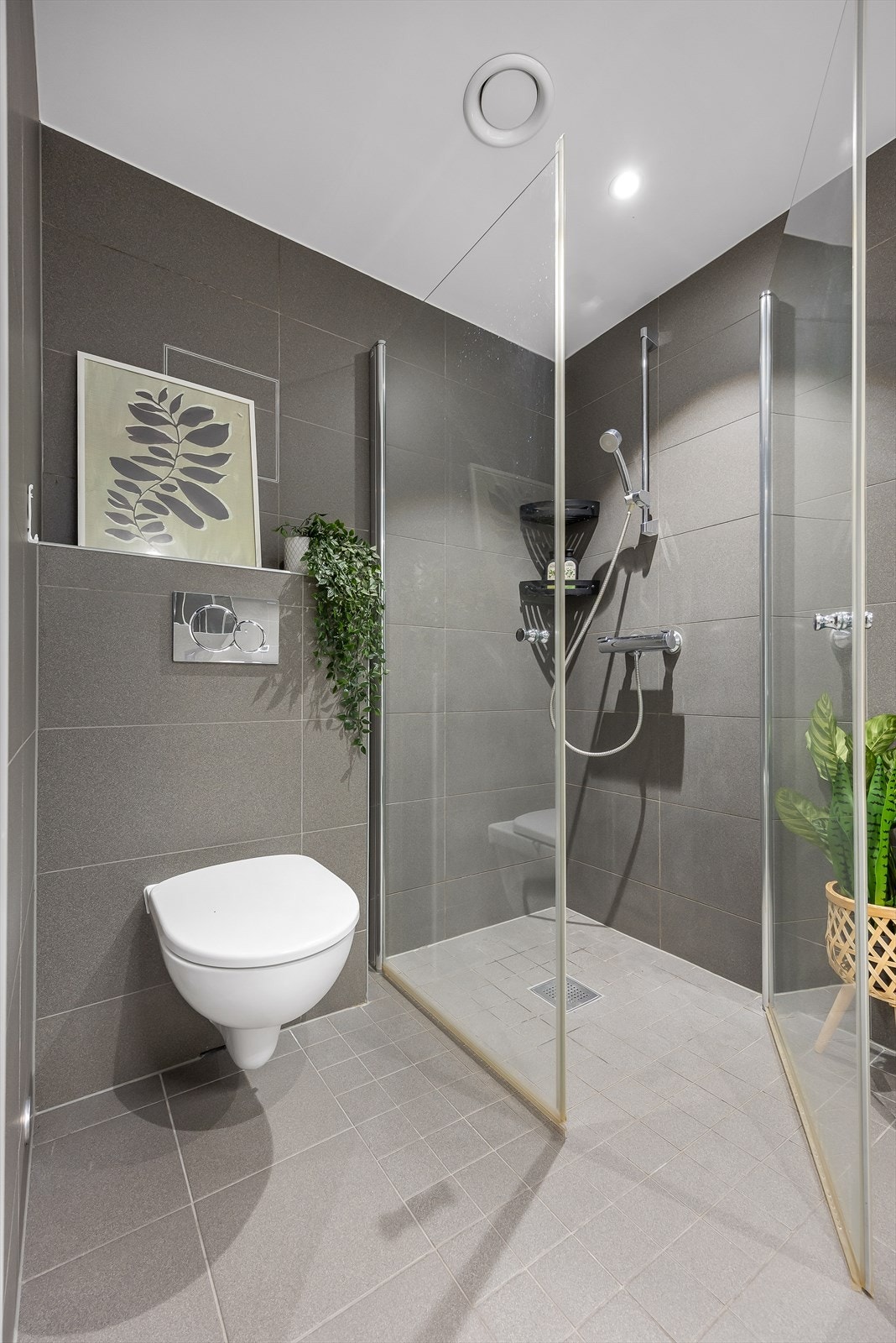 Badet er utstyrt med vegghengt toalett og dusjhjørne med innfellbare glassdører. Galleribilde