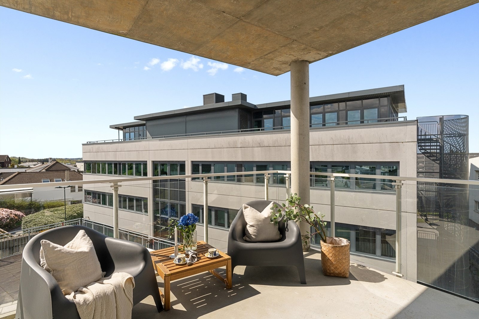 Balkongen har et solid betonggulv og et moderne rekkverk i glass. Galleribilde