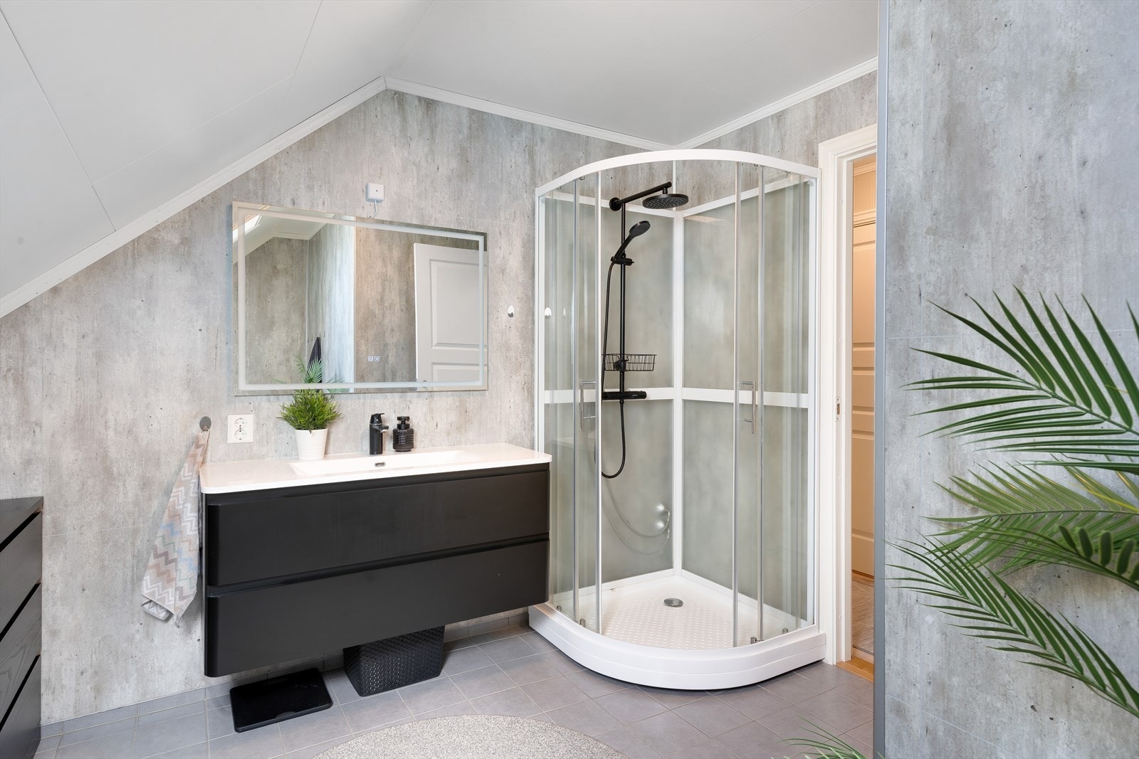 Badet har flislagt gulv med varmekabler og er innredet med servant, veggmontert toalett, dusjkabinett og badekar. Galleribilde