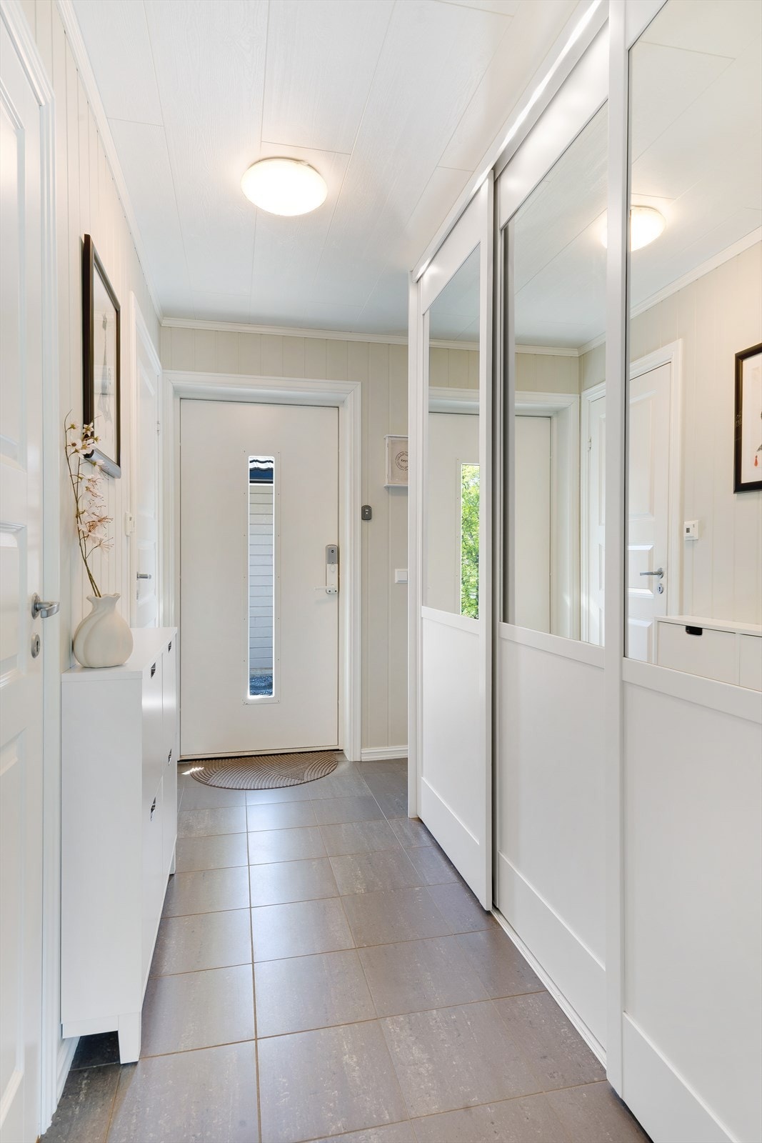 Skyvedørsgarderobe med speil gir praktisk oppbevaringsløsning i entréen. Her har du inngang til bad, bod/teknisk rom og stuen. Galleribilde