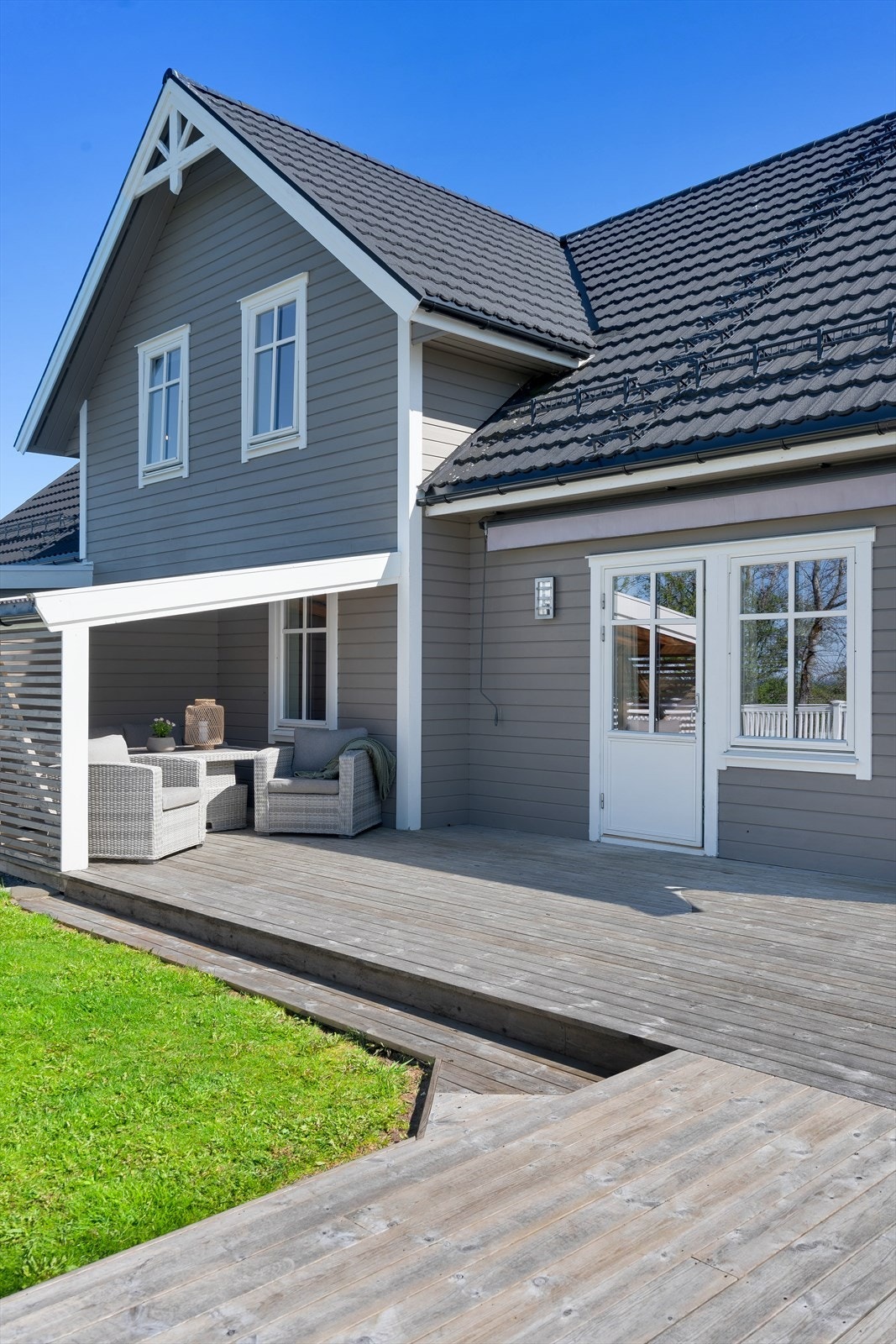 Pent opparbeidet uteområde mot vest med terrasse, plen og et takoverbygd hjørne som skaper en lun og skjermet uteplass. Galleribilde