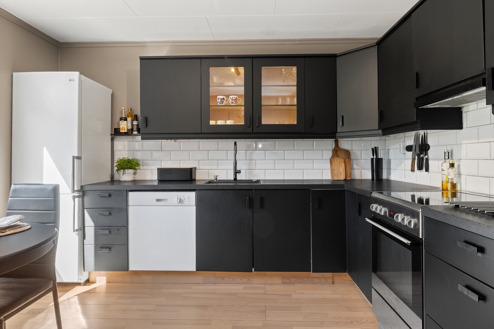 Innredning i L-form med svarte glatte oveflater Galleribilde