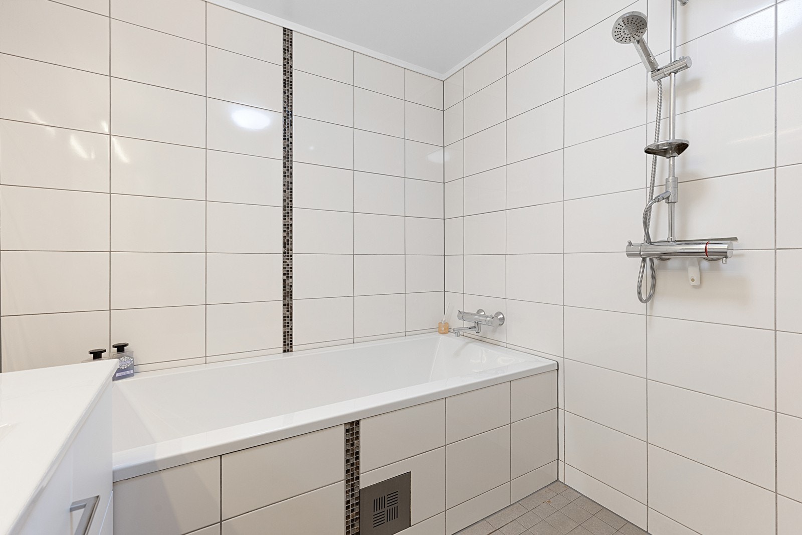 Lekkert flislagt bad med dusj, badekar, servant og toalett Galleribilde