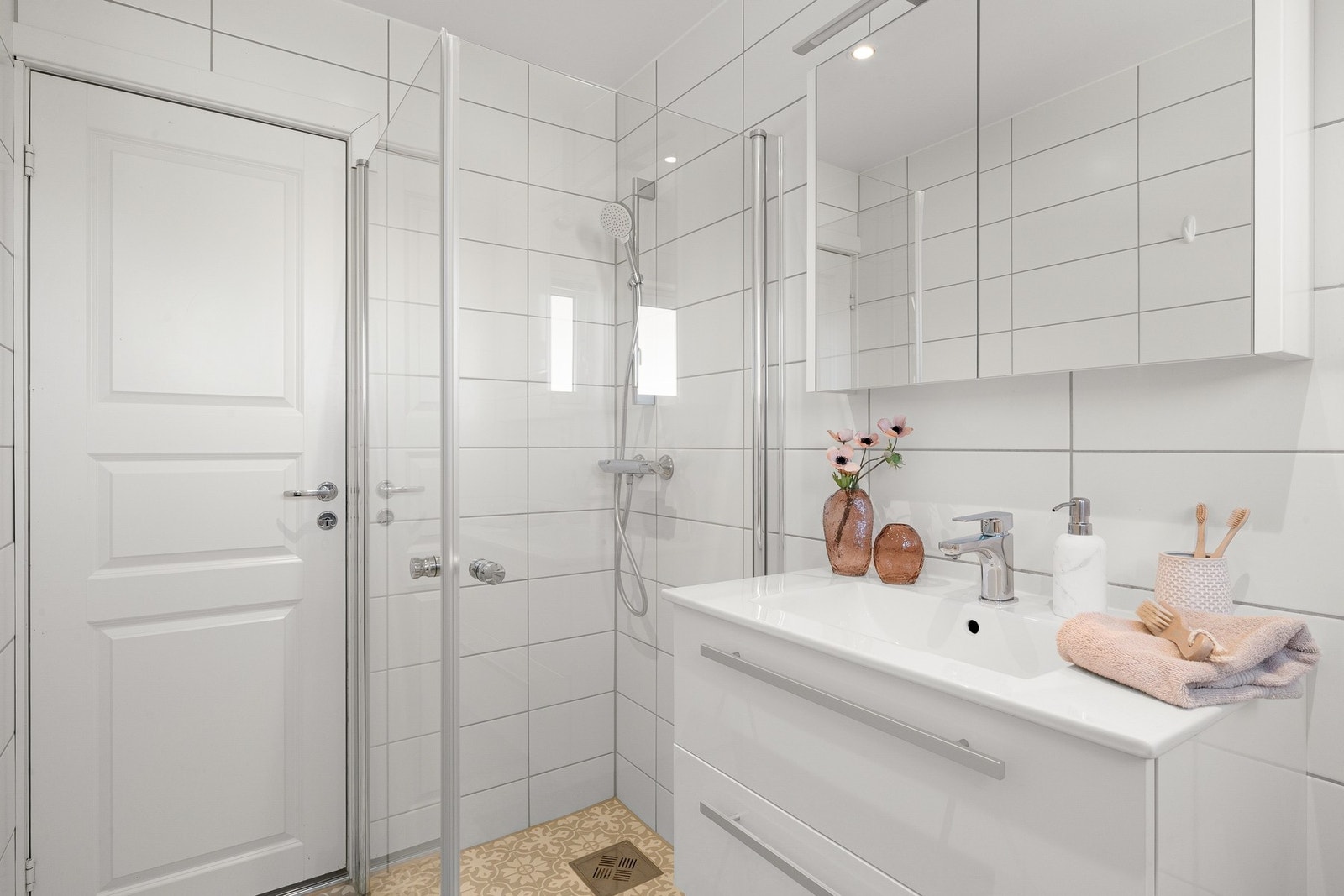 Videre er badet innredet med dusjvegger i glass, servantinnredning med underskap og toalett. Galleribilde