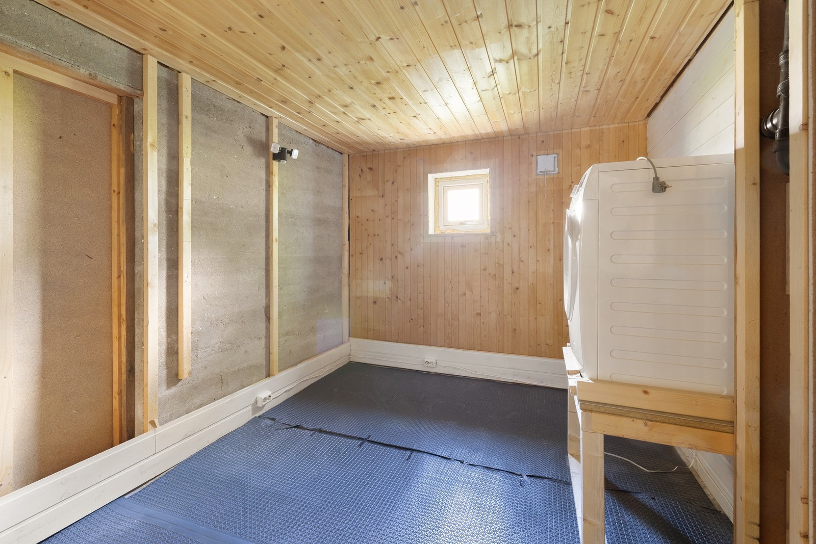 Vaskerom i kjeller med betonggulv og opplegg for vaskemaskin. Galleribilde