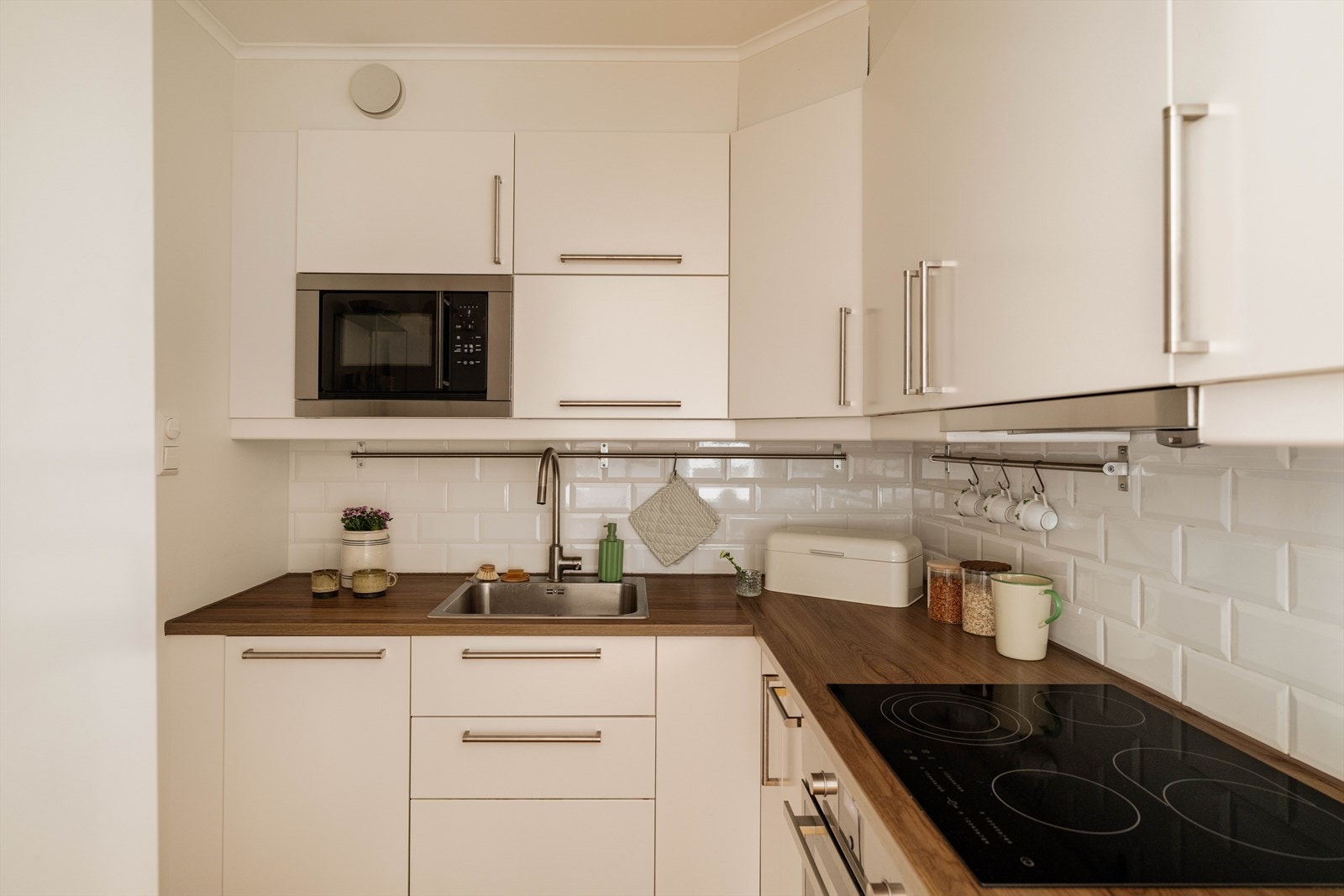 Kjøkkeninnredning fra IKEA, oppgradert i 2017, med glatte fabrikklakkerte fronter og laminat benkeplate med nedfelt kum i rustfritt stål, som gir et rent og funksjonelt uttrykk. Galleribilde