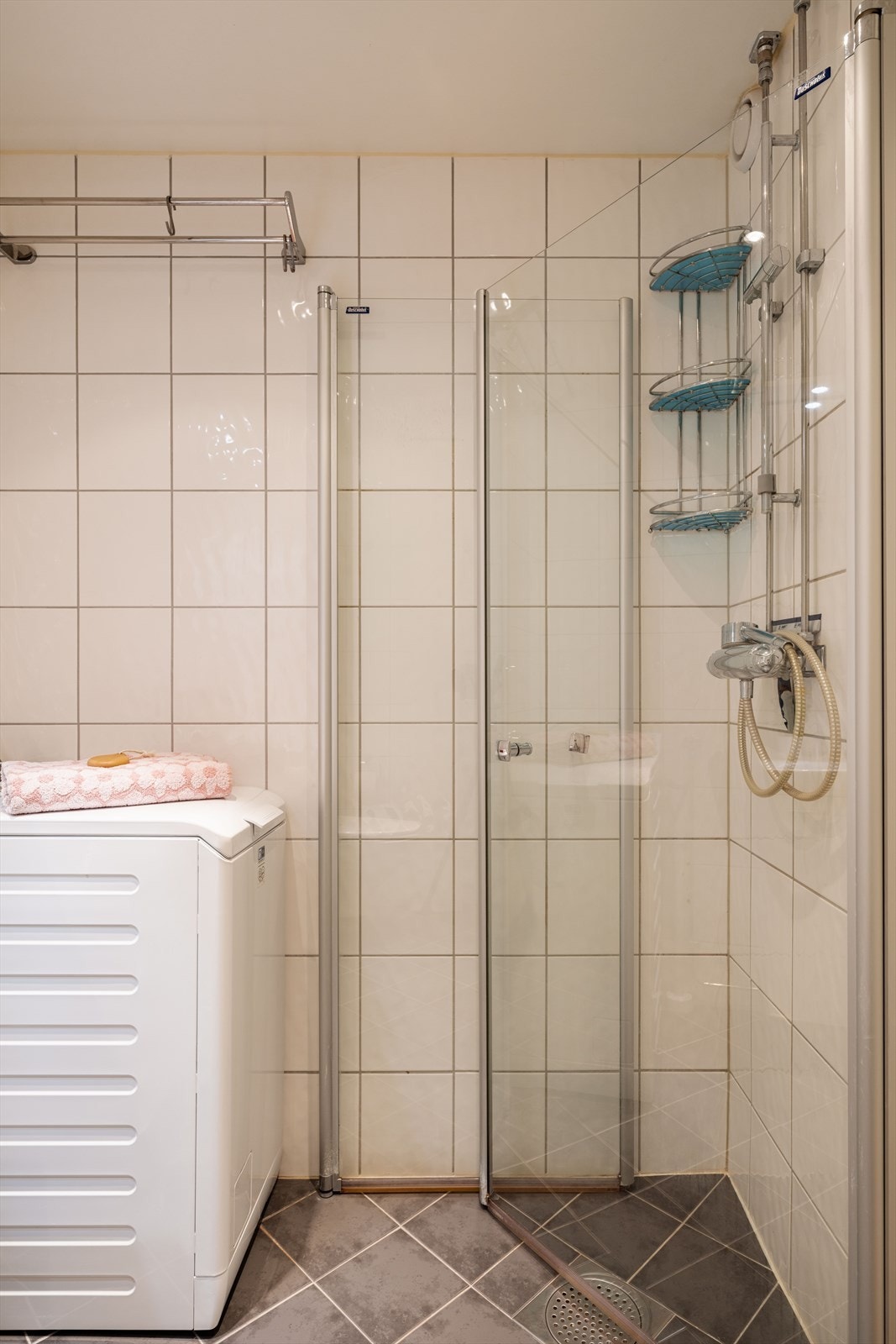 Dusjhjørne med svingdører, hånddusj og termostatstyrt blandebatteri. Praktisk opplegg for smal vaskemaskin. Galleribilde