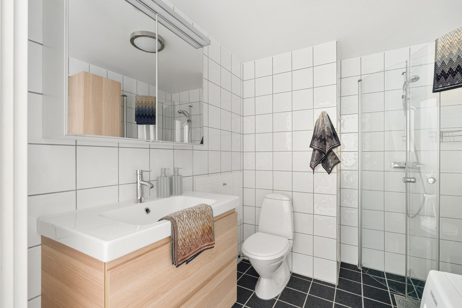 Baderommet består av dusjsone, gulvmontert WC, servant, underskap, speil og veggskap. Galleribilde