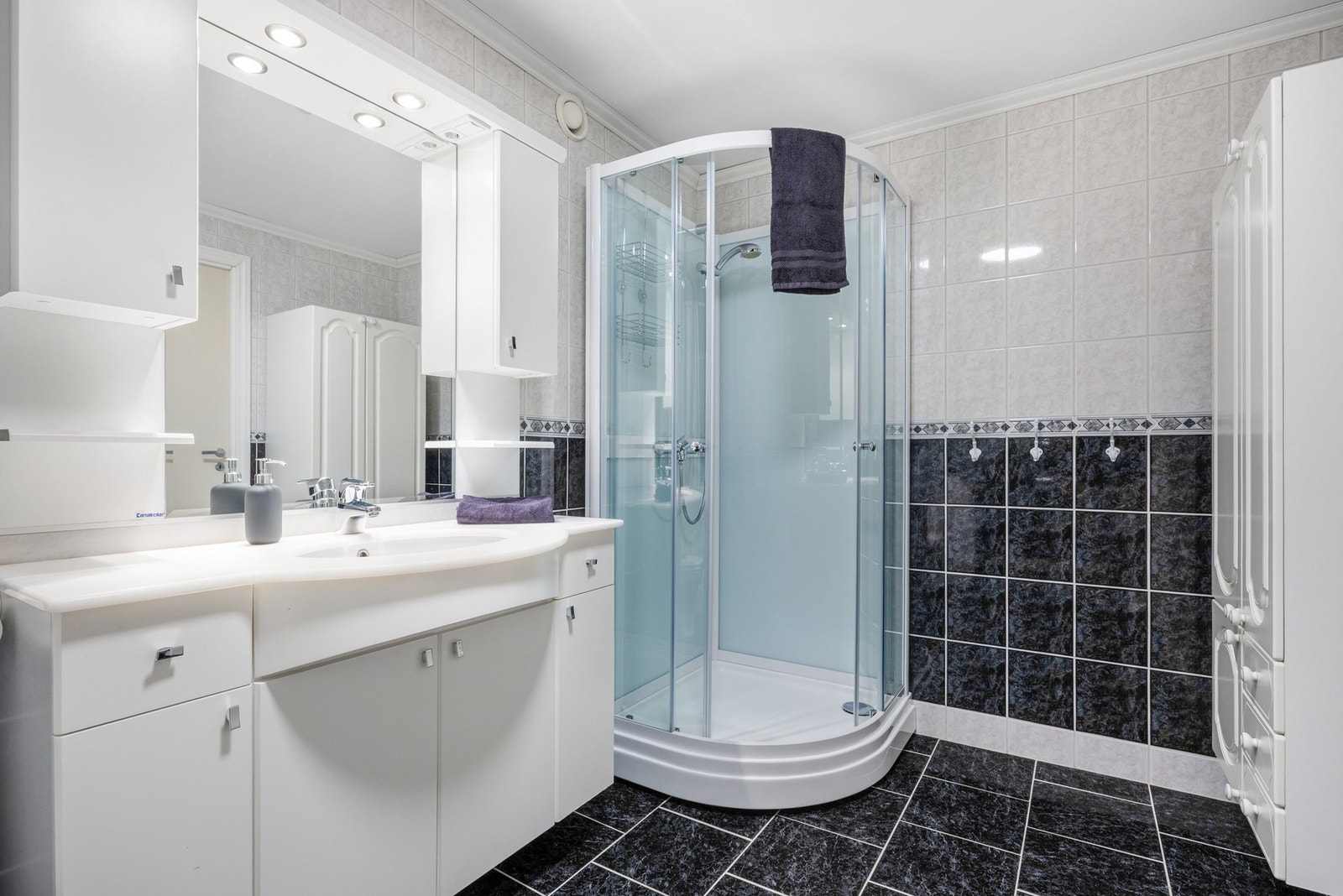 Badet er helfliset og er innredet med dusjkabinett, baderomsmøbel med nedfelt servant, toalett, utslagsvask og opplegg til vaskemaskin / tørketrommel Galleribilde