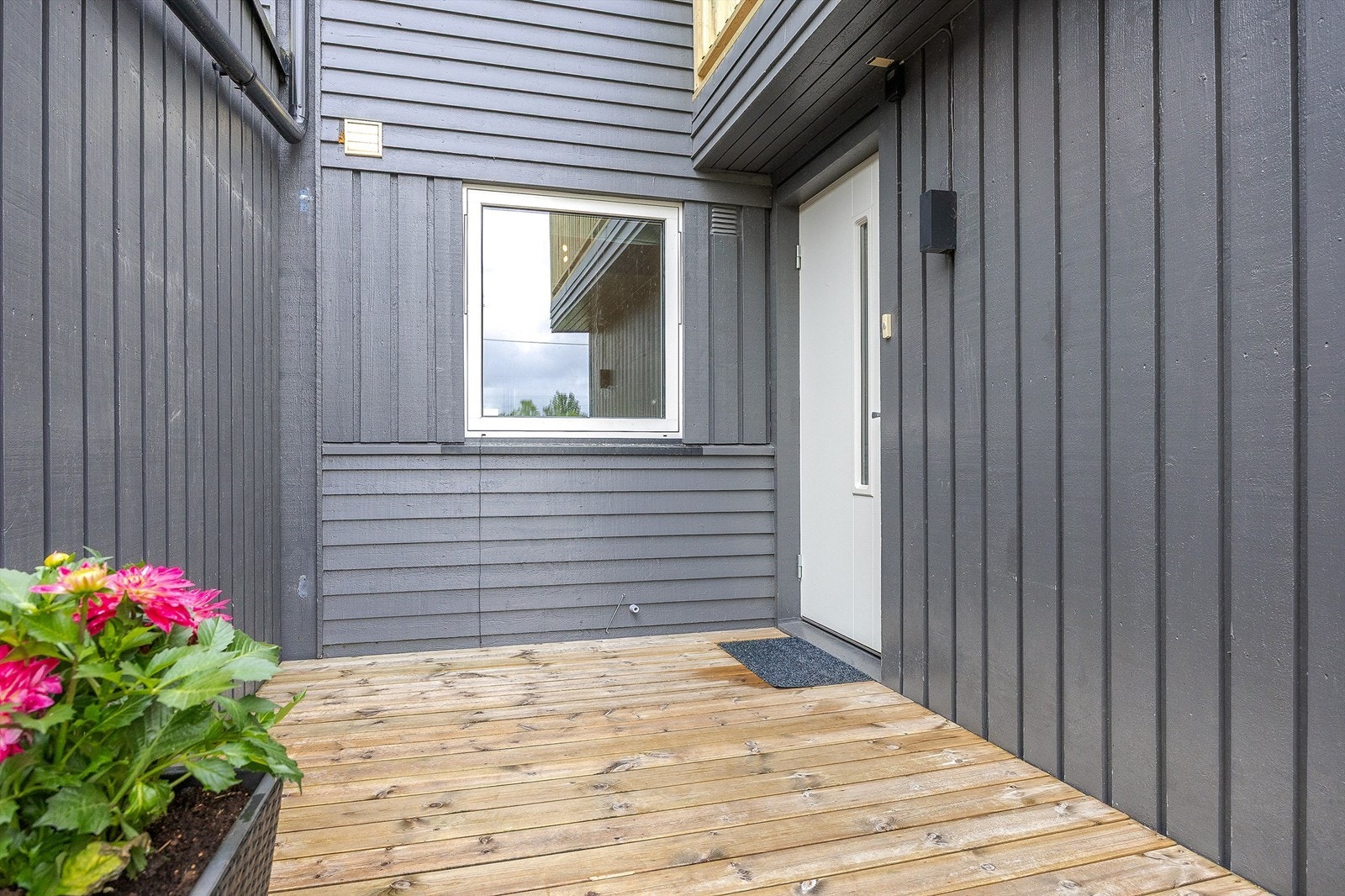 Overbygget inngangsparti med plass til en liten sittegruppe. Galleribilde