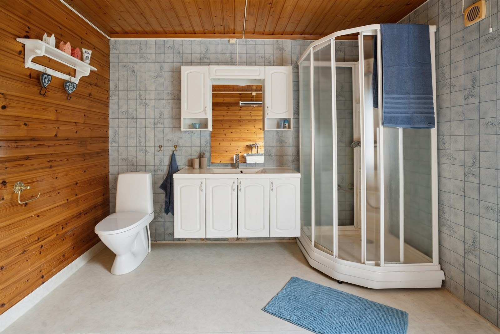 Badet er utstyrt med dusjkabinett, servant med innredning og gulvklosett. Galleribilde