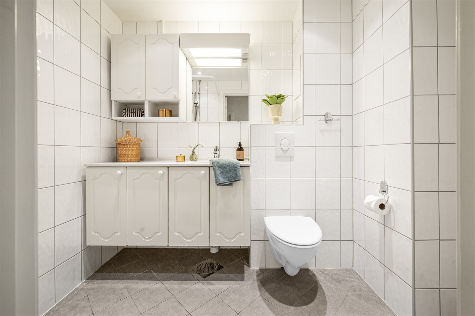 Badet er utstyrt med vegghengt toalett, dusj og baderomsinnredning med servant. Galleribilde