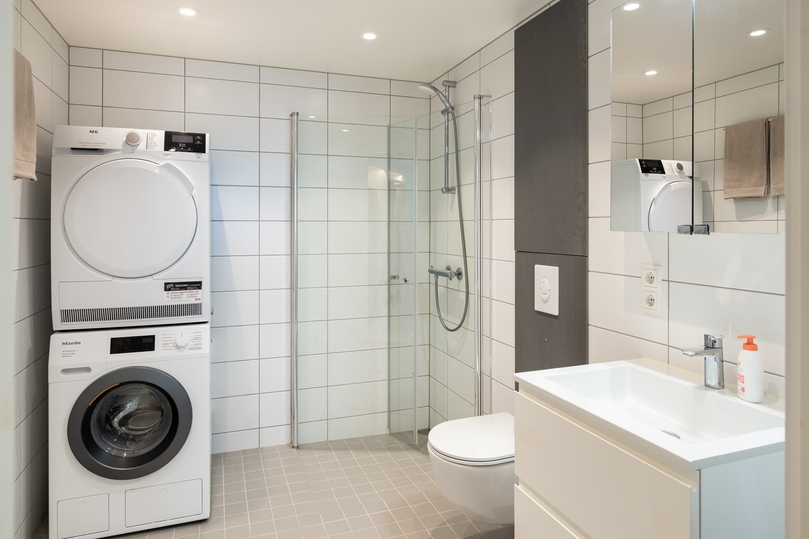 Badet byr på vegghengt servantinnredning, dusjhjørne med dører, vgghengt toalett og opplegg for vaskemaskin. Galleribilde
