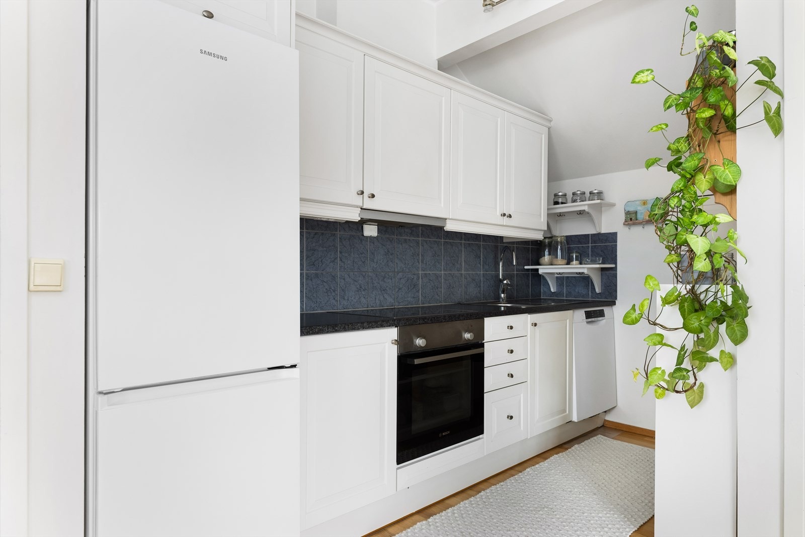 Kjøkkeninnredning med profilerte fronter, laminatbenkeplate, platetopp, stekeovn og oppvaskmaskin. Galleribilde