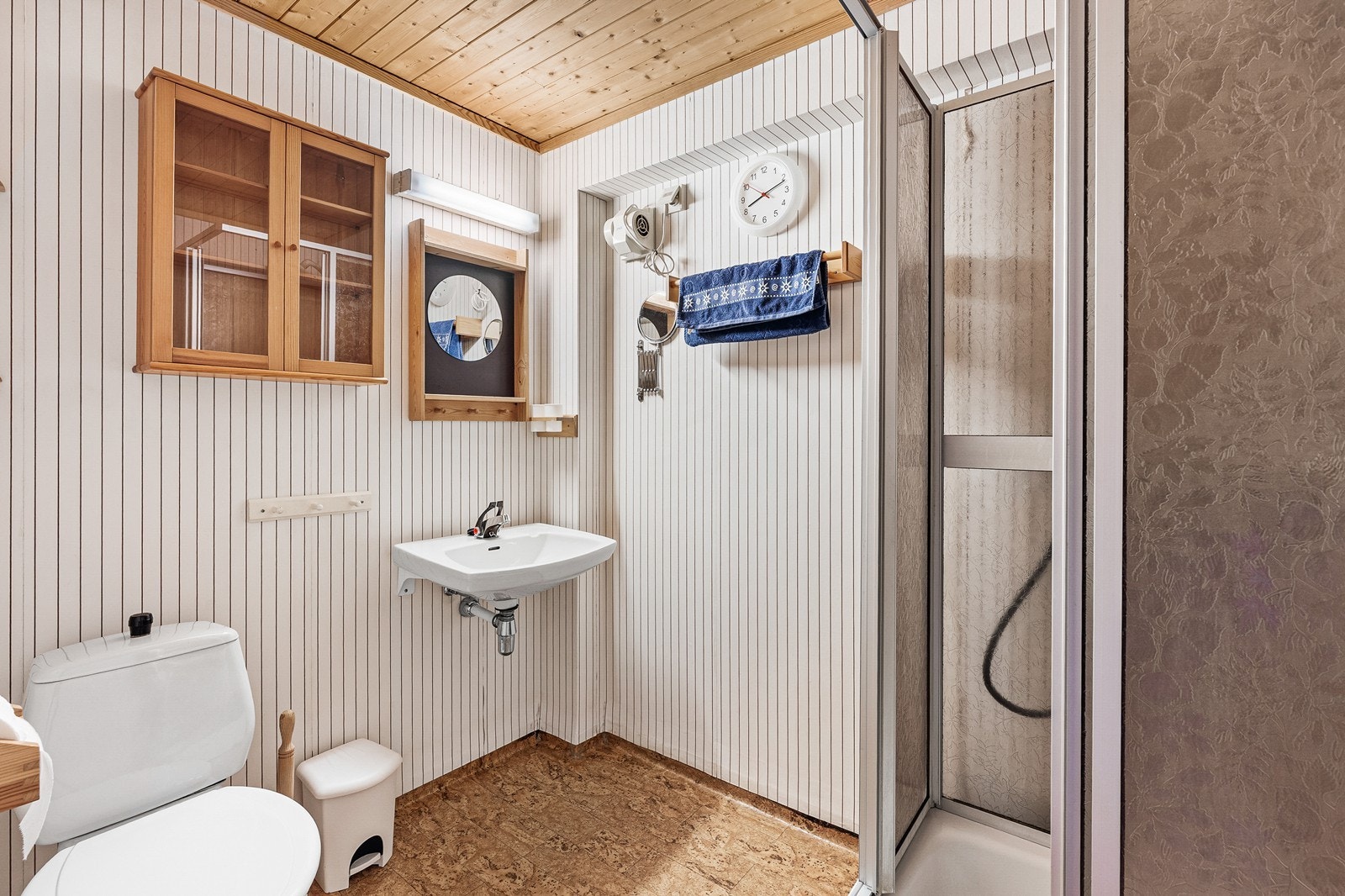 Badet er innredet med servant, toalett og dusjakbinett. Det er vinyltapet på vegger og panel i himling. Galleribilde