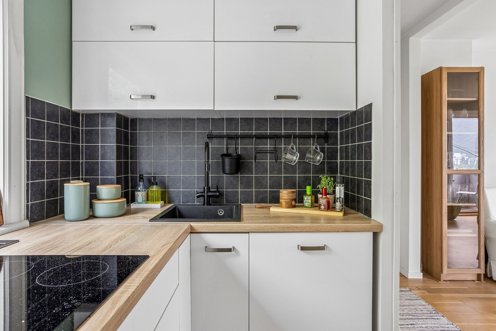 Kjøkkeninnredning med laminatbenkeplate, fliser over benken og integrert induksjonstopp. Galleribilde
