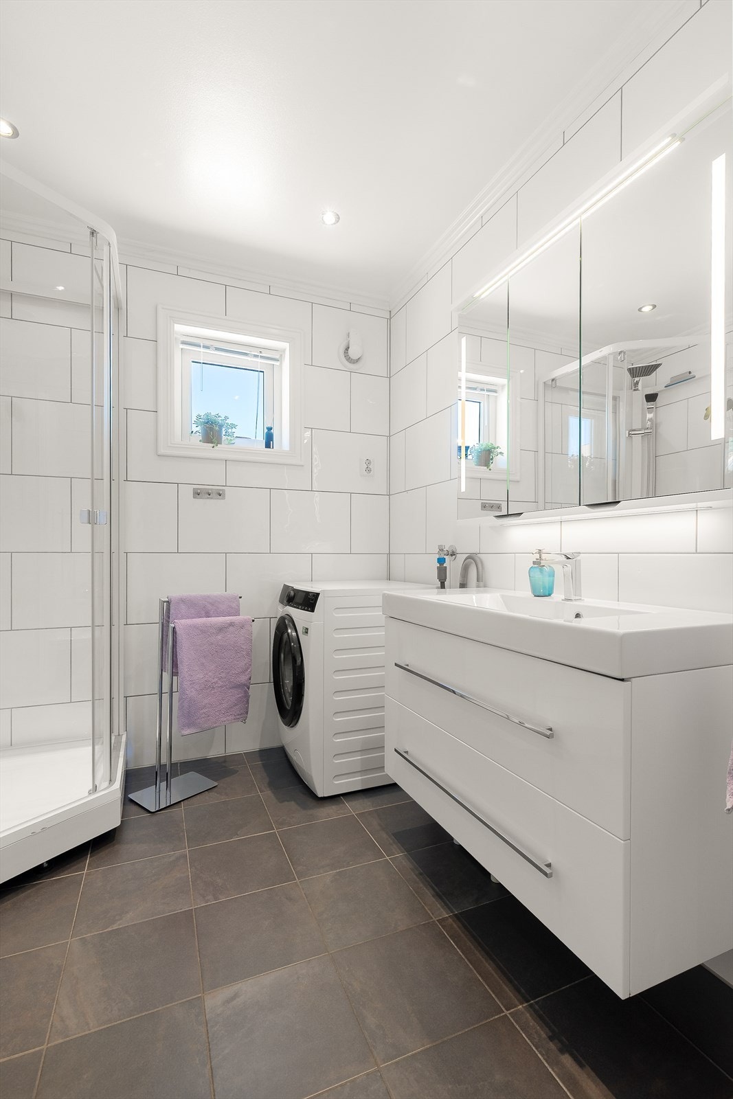 Badet er utstyrt med dusjkabinett, toalett og en moderne servantinnredning med god oppbevaringsplass. Galleribilde