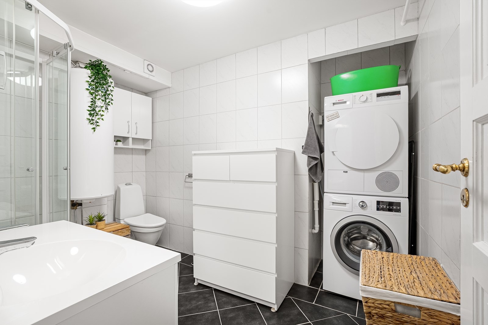 Lyst og moderne bad med dusjkabinett, god oppbevaringsplass og praktisk sone for vaskemaskin og tørketrommel Galleribilde
