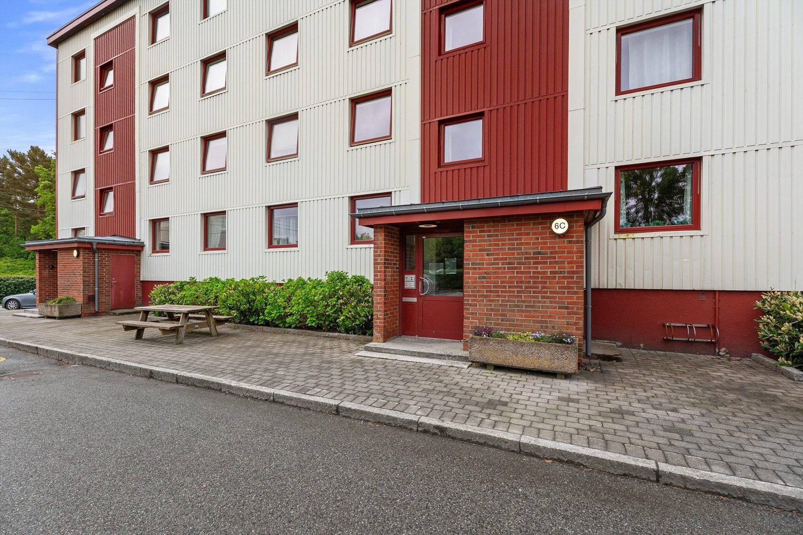 Pent og velholdt inngangsparti med sittebenk og beplantning - et hyggelig førsteinntrykk av bygget Galleribilde