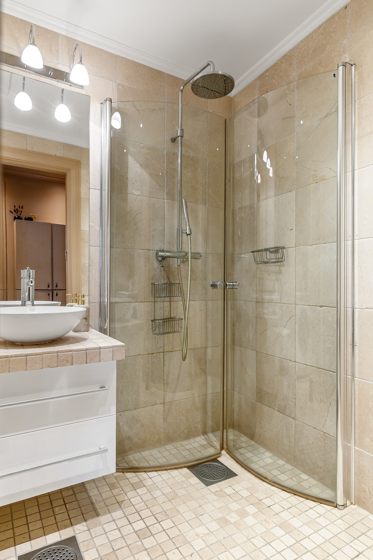 Badet er innredet med servantskap med toppservant, speil med belysning, vegghengt toalett og dusjsone. Galleribilde