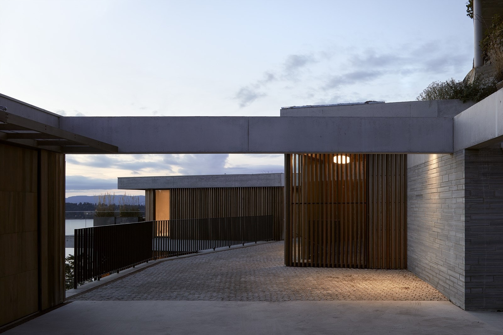 Garasje og adkomstareal er integrert i byggets arkitektur med trepanel og skjermet plassering Galleribilde