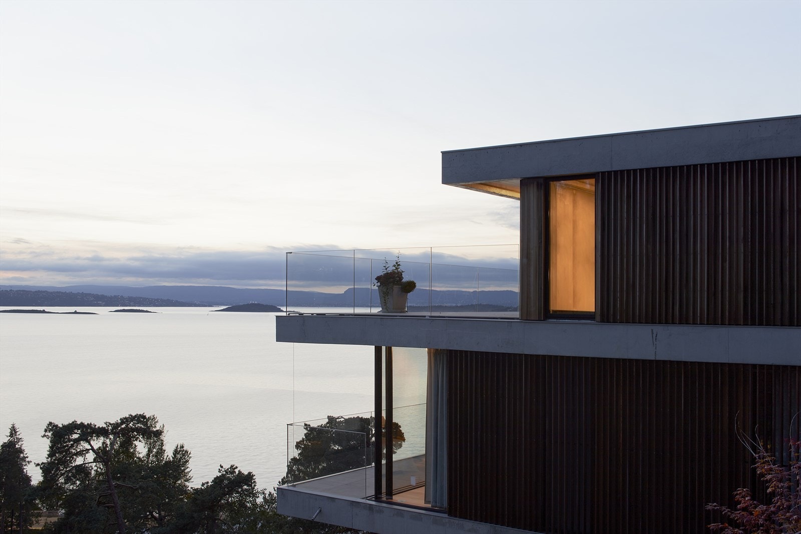 Solnedgang og fjordutsikt rammer inn boligens private utearealer og åpne plassering Galleribilde