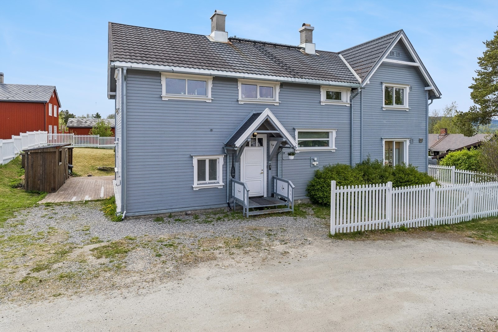 Eiendommen ligger på en flat og delvis skrånet tomt, beplantet med plen og trær. Galleribilde