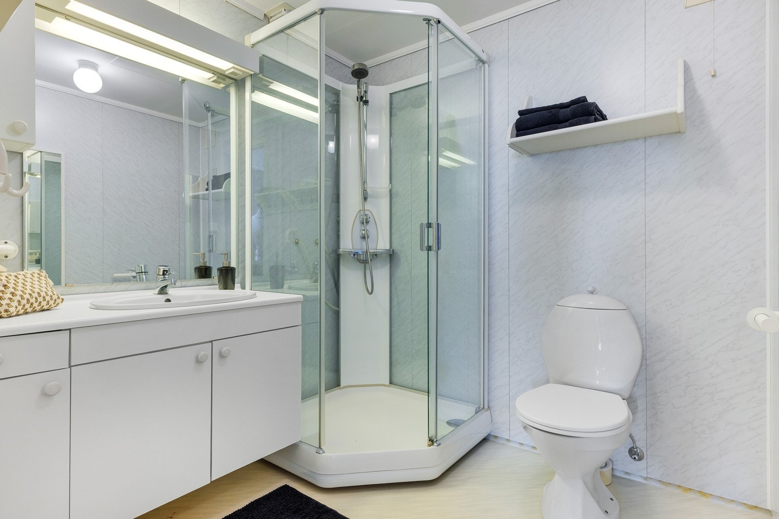 Baderom med wc, dusjkabinett og servant med skap og speil. Galleribilde