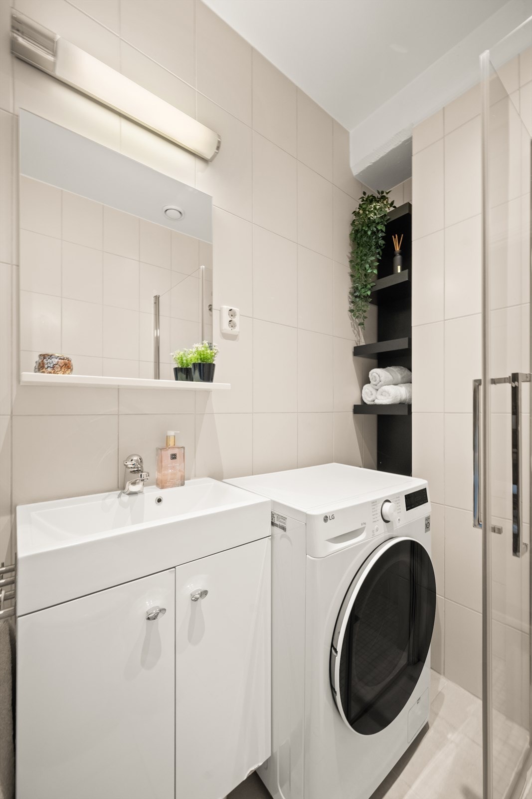 Badet er innredet med klosett, dusjhjørne med nyere innfellbare glassdører og baderomsmøbel med skap, nedfelt servant, speil og belysning. Det er opplegg for vaskemaskin. Galleribilde