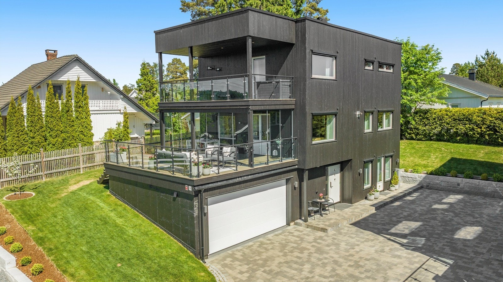 Fasaden har stående bordkledning og et moderne uttrykk med store vindusflater. Galleribilde