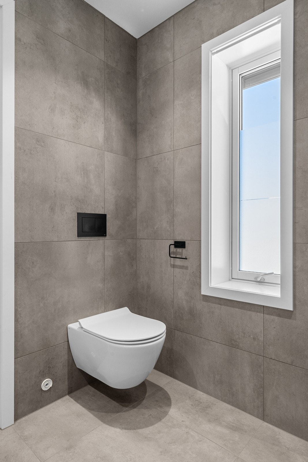Badet har vegghengt toalett og gjennomgående, moderne materialvalg. Galleribilde