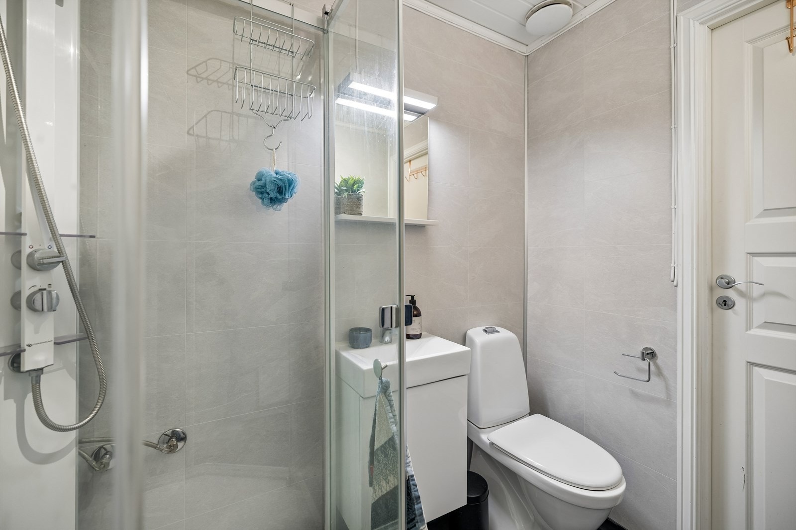 Badet har inredning som består av servant, speilhylle med lys, gulvmontert toalett samt dusjkabinett. Galleribilde