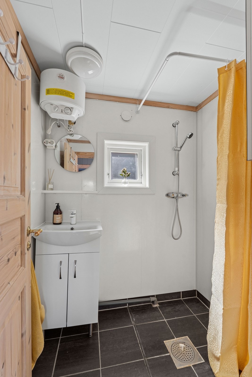 Badet i annekset har flislagt gulv, baderomsplater på veggene og dusj. Her er også varmtvannstanken plassert. Galleribilde