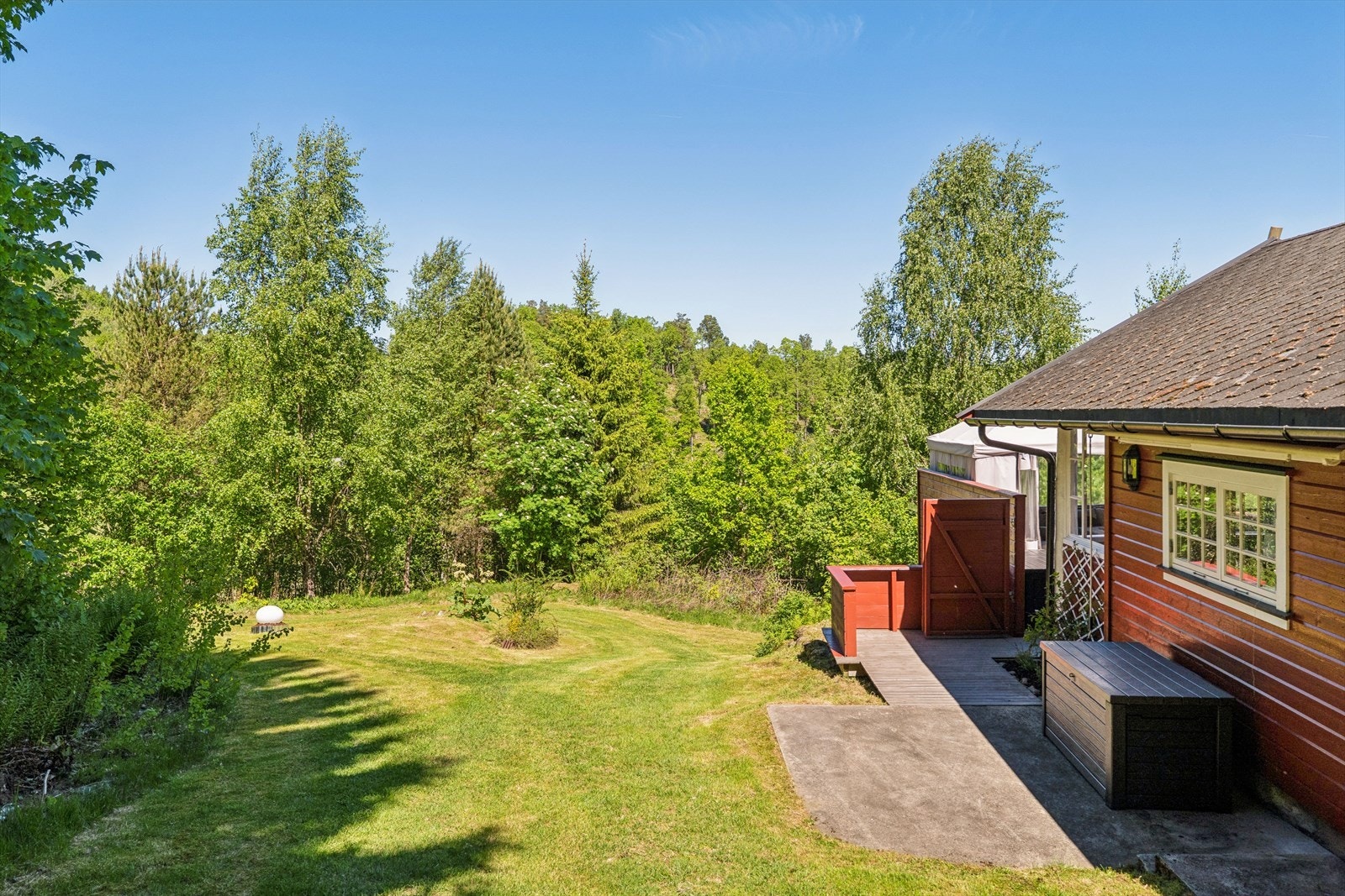 Tomten er omgitt av grøntarealer og natur, og ligger i et skrånende terreng. Galleribilde