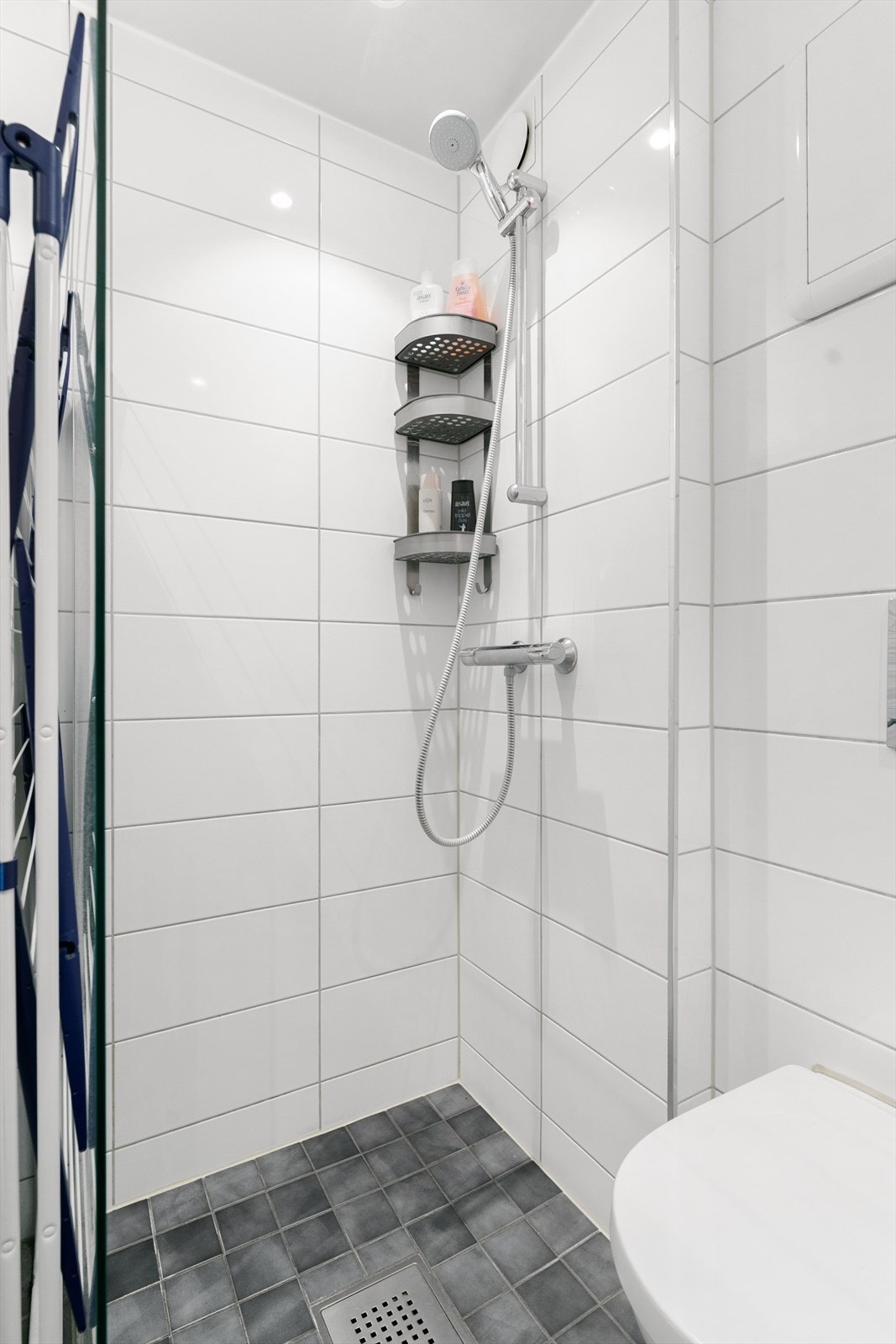 Innredningen består av vegghengt wc, servant i hvit skuffeseksjon med speil og belysning over, samt dusjsone. Galleribilde