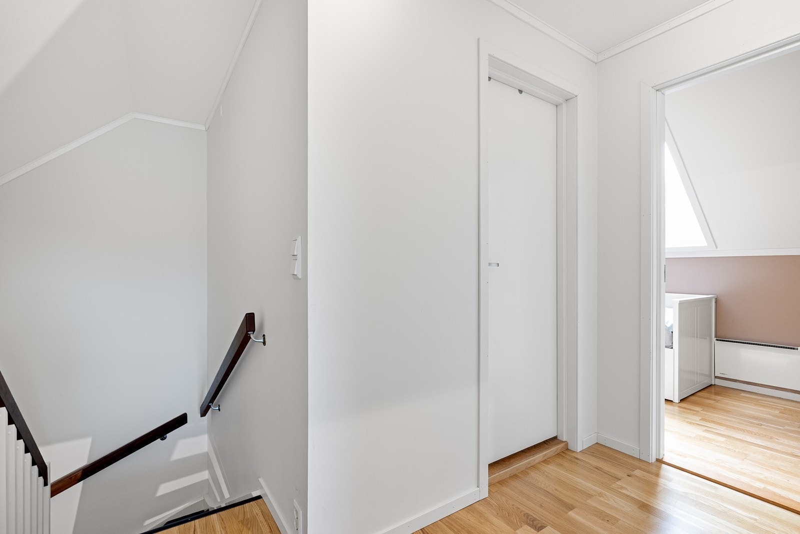 Hvit tretrapp med sving og brubbeisede trinn gir tilgang til boligens andre etasje. Galleribilde
