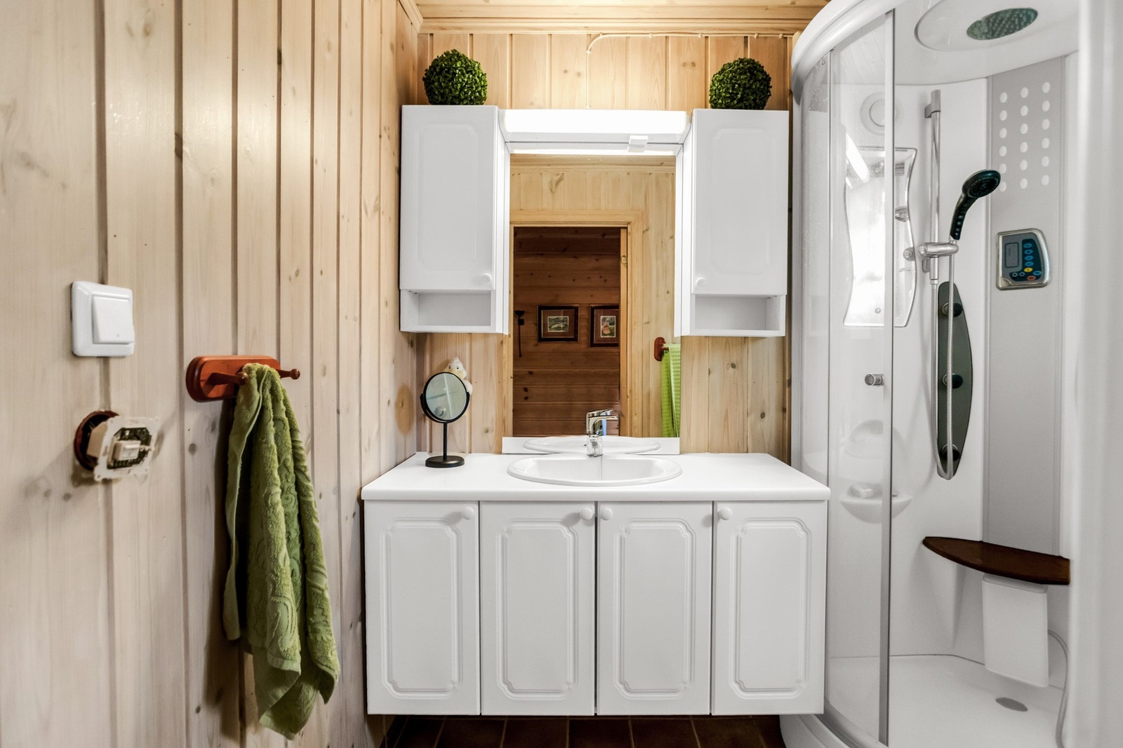 Badet har et flislagt gulv med elektriske varmekabler, og vegger og tak er kledd med trepanel. Galleribilde