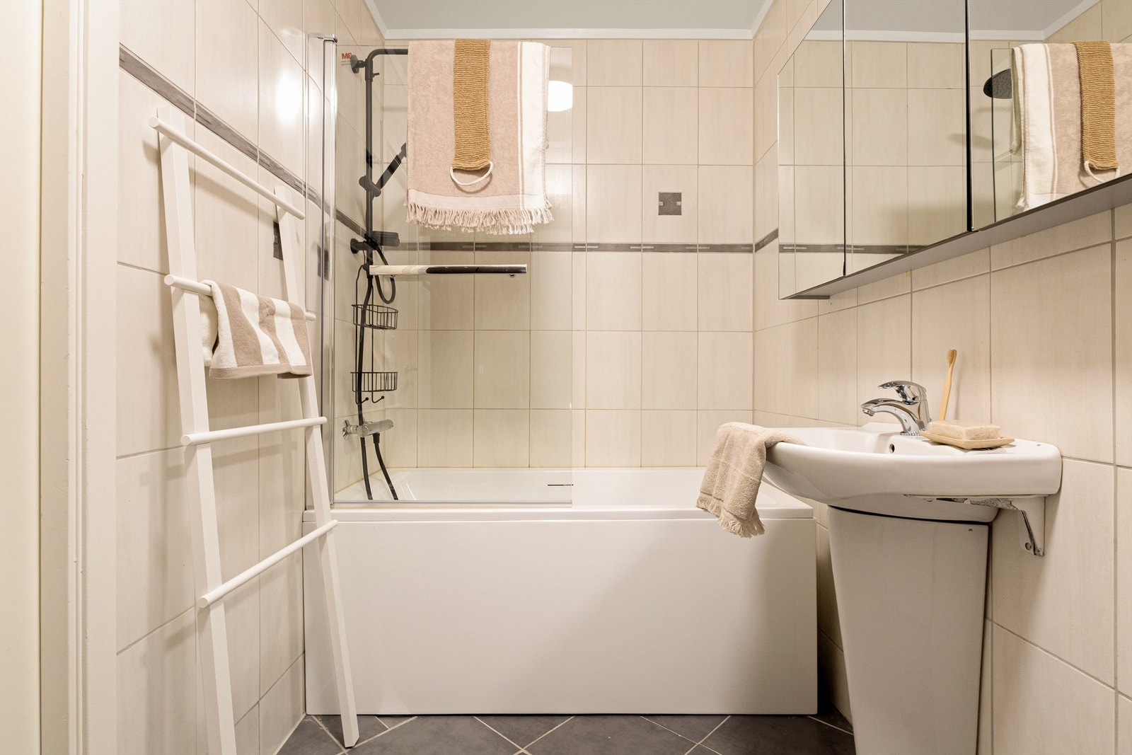 Badet er utstyrt med dusjløsning i badekaret og speilskap for oppbevaring. Galleribilde